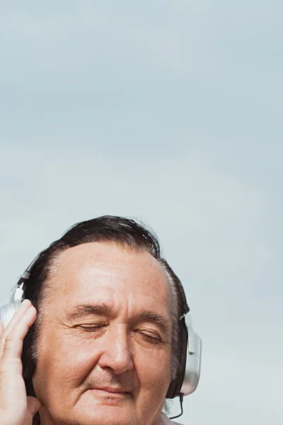 Homem idoso ouvindo fones de ouvido — Fotografia de Stock