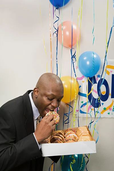 Businessman secretly eating doughnuts — Stock Photo, Image