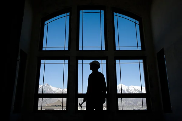 Silhouette of a builder against a window — Stock Photo, Image