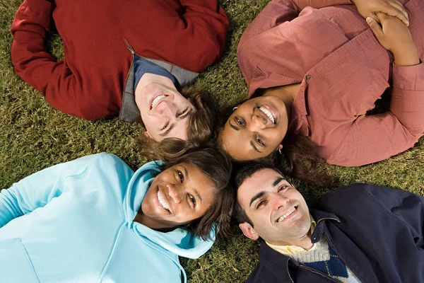 Quatro estudantes deitados ao ar livre — Fotografia de Stock