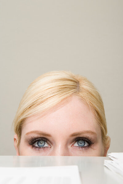 Woman peeking over filing cabinet