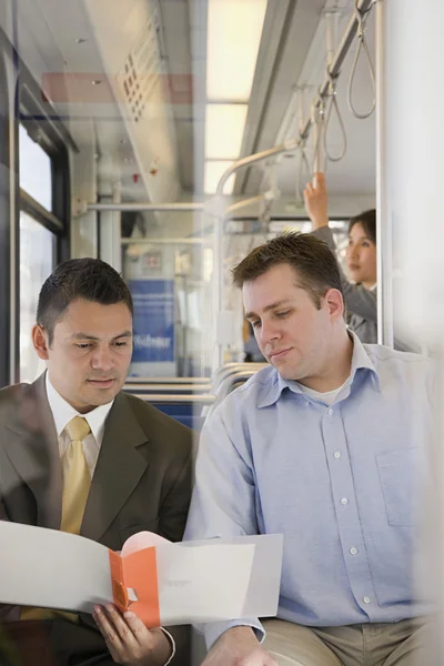 Des hommes regardent un dossier en train — Photo