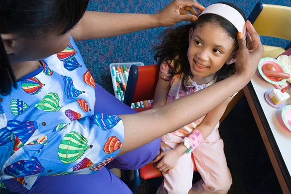 Nurse putting headband on girl — Stock Photo, Image