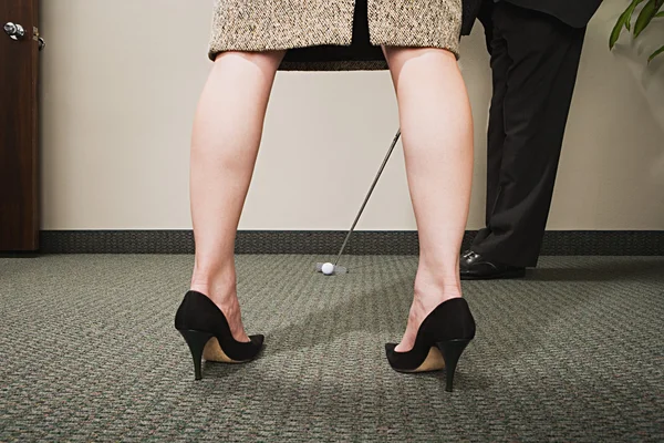 Člověk hraje golf prostřednictvím ženské nohy — Stock fotografie