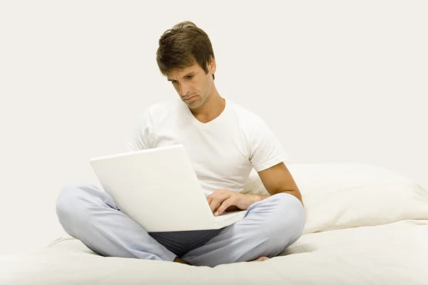 Man zit op bed met behulp van laptop — Stockfoto