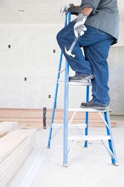 Een bouwer houden een hamer op ladder — Stockfoto