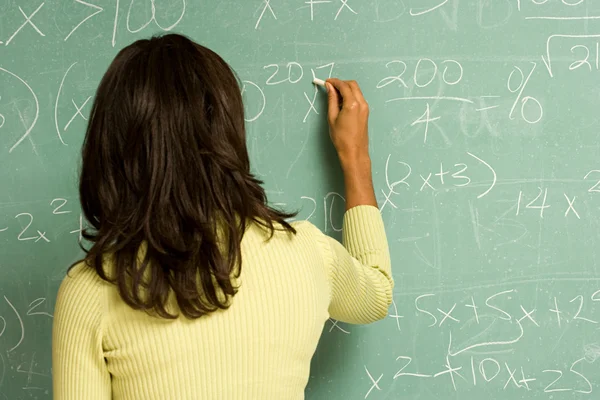 Female student writing on blackboard — Stock Photo, Image