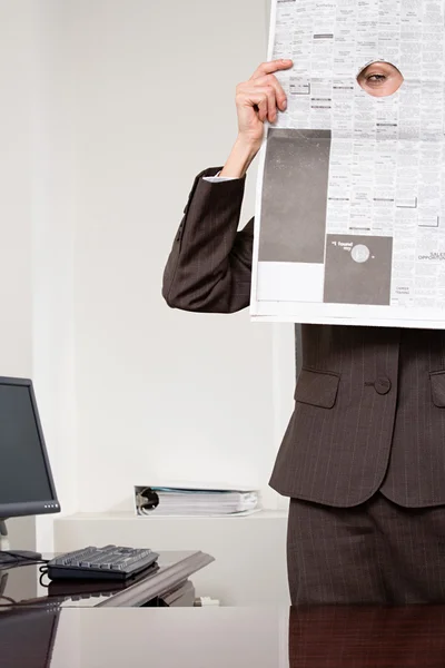 Woman looking through hole in newspaper — Stock Photo, Image