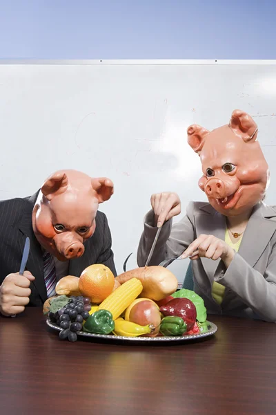 Businesspeople in pig masks with plastic food — Stock Photo, Image