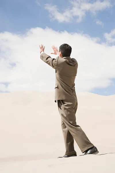 Businessman in desert under clouds sky — Stock Photo, Image