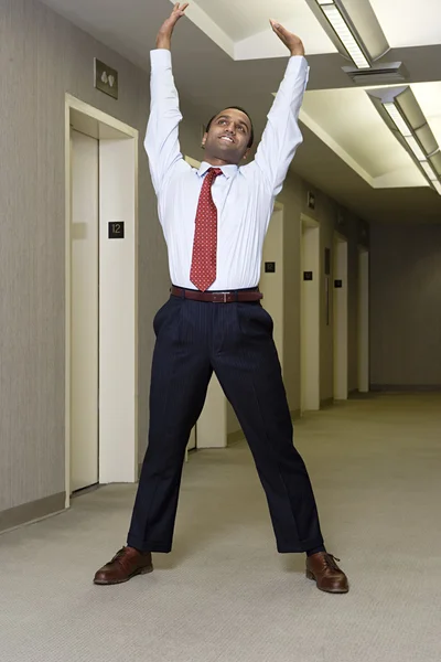 Office worker stretching in corridor — Stock Photo, Image