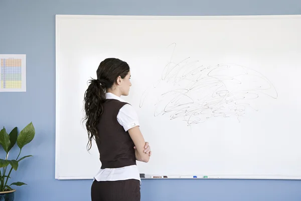 Woman looking at scribble on whiteboard — Stock Photo, Image