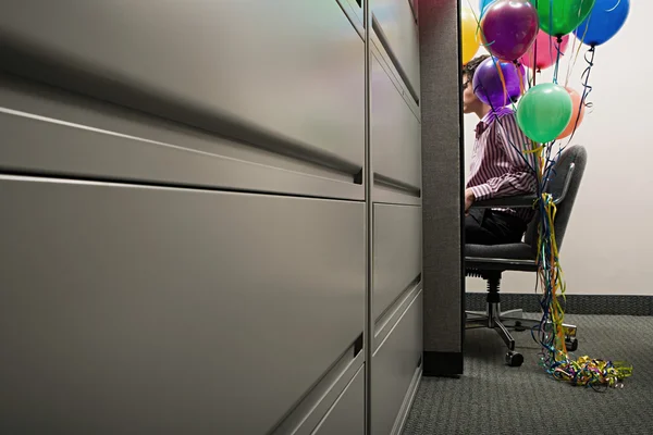 Businessman sat with balloons tied to his chair — Stock Photo, Image
