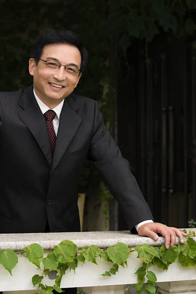 Smiling businessman leaning on a ledge — Stock Photo, Image