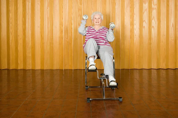 Äldre kvinna utövar holding hantlar — Stockfoto