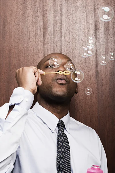 Businessman blowing bubbles — Stock Photo, Image