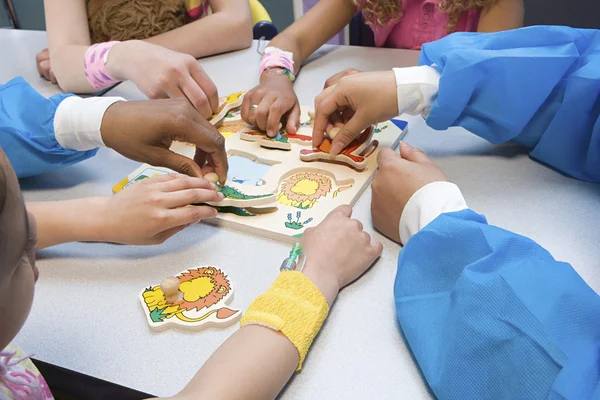 Bambini e infermieri che giocano con puzzle — Foto Stock