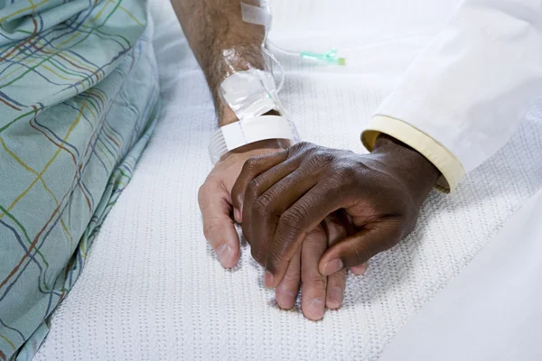 Врач держит пациента за руку — стоковое фото