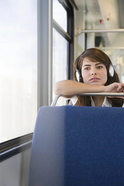 Женщина в наушниках едет на поезде — стоковое фото