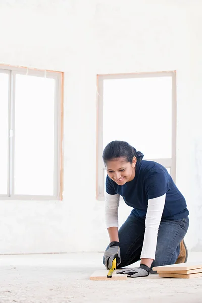 A female builder measuring a plank of wood Stock Picture