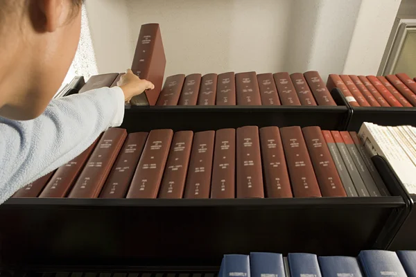 Female student reaching for a book Royalty Free Stock Photos