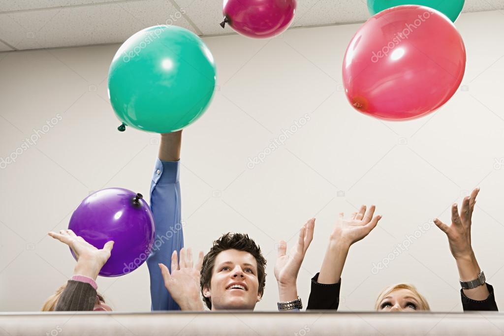Office workers playing with balloons