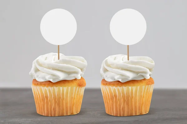 Two frosted gold cupcakes relaxing on an elegant gray marble background.