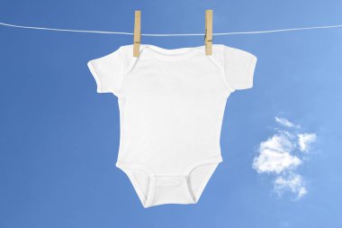 Güzel mavi bulutlu gökyüzüne karşı çamaşır ipinde asılı duran beyaz tulum..