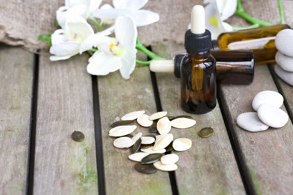 Pompoenpitten olie in een fles van de druppelaar op een oud hout. Closeup — Stockfoto