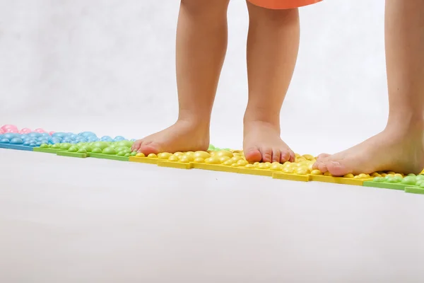 Детские лапки на ортопедическом коврике — стоковое фото