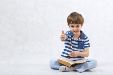 Bir çocuk beyaz bir arka plan üzerine bir kitap okuyor