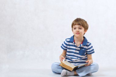 Bir çocuk beyaz bir arka plan üzerine bir kitap okuyor