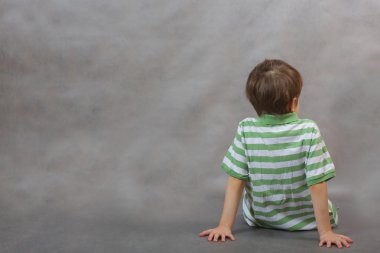 Bir oğlan döndü sırtı ile oturuyor