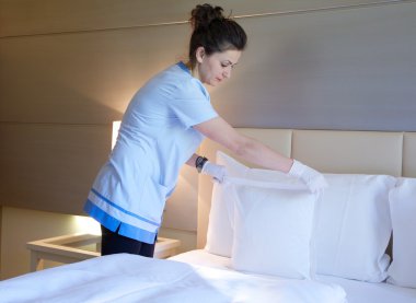 Temizlikçi kadın yatağı yapıyor
