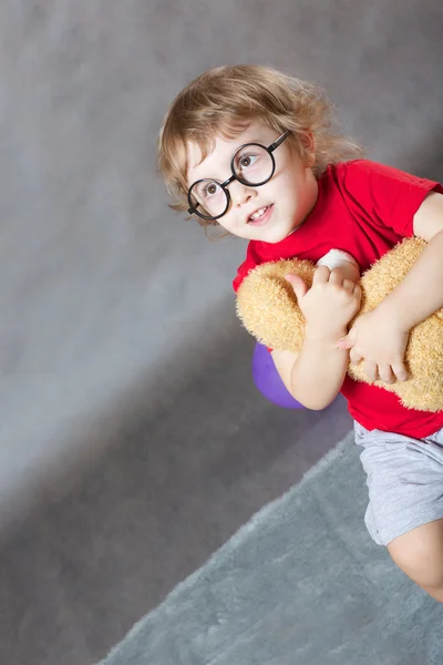 Un niño con un osito de peluche en sus brazos — Foto de Stock