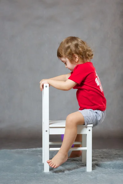 A boy and a white chair. Gray background — Stock Photo, Image