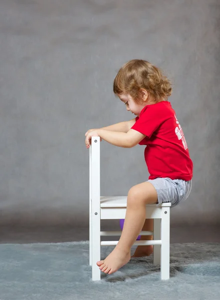 A boy and a white chair. Gray background — Stock Photo, Image