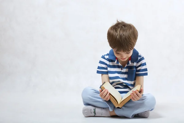 Мальчик читает книгу на белом фоне — стоковое фото