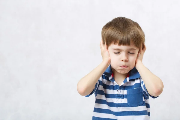 Um rapaz cobre os ouvidos e fecha os olhos. . — Fotografia de Stock