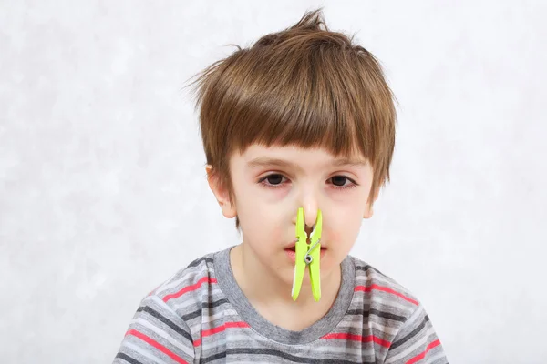 Un garçon avec une pince à linge sur le nez . — Photo