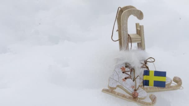 冬のスポーツ用具のそり スケートシューズ スウェーデンの国旗 雪の背景 — ストック動画