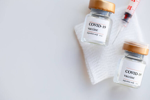 Два флакона с вакциной COVID-19 на стерильном мазке гаузы. Шприц на заднем плане. Плоский лежал