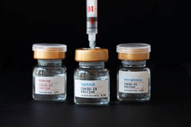Vials of three COVID-19 vaccines on a black background. Closeup clipart
