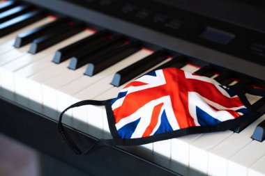Piyano klavyesinde İngiliz bayrak kumaşı maskesi. Yakın çekim.
