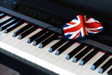 Piyano klavyesinde İngiliz bayrak kumaşı maskesi. Yakın çekim.