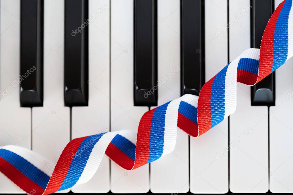 Russian flag ribbon on piano keyboard. Closeup