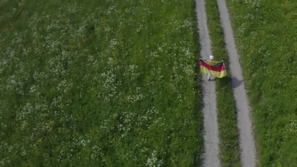 フィールドの村のパスに沿ってドイツのフラグで実行されている8歳の男の子 — ストック動画
