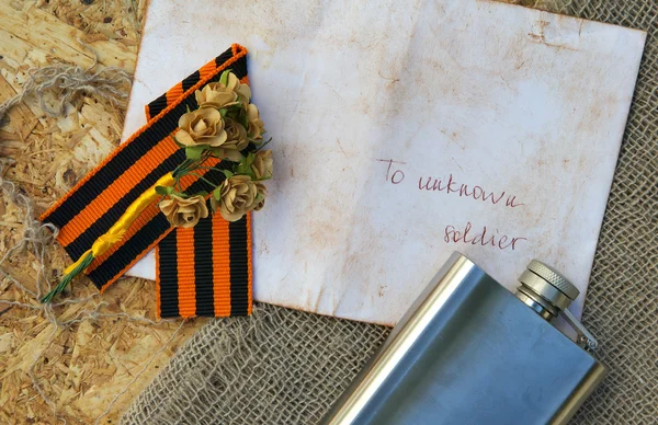 Бумажные цветы, лента Святого Георгия, фляжка на мешковине — стоковое фото