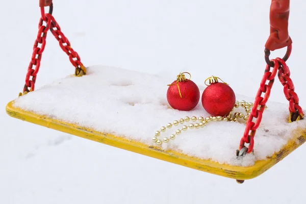 Kerstballen in de sneeuw op een schommel stoel — Stockfoto