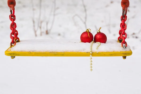 Bolas de Natal na neve em um assento de balanço — Fotografia de Stock